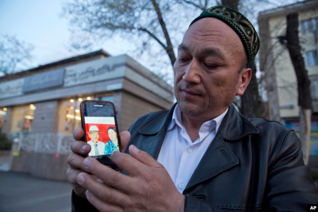 2018年3月31日，Omir Bekali在哈萨克斯坦阿拉木图拿着手机，上面显示了他父母的照片，他认为父母在中国被拘留。