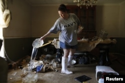 Marilyn Mays drains water from dishes in the dining room of her mother's home after heavy rains led to flooding in Denham Springs, Louisiana, Aug. 17, 2016.