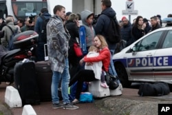 Travelers wait outside the Orly airport, south of Paris, March, 18, 2017. A man was shot to death after trying to seize the weapon of a soldier guarding Paris' Orly Airport.