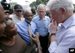 El expresidente de Haití, Rene Preval, segundo a la izquierda, el expresidente George W. Bush, al centro, y el expresidente y enviado especial de la ONU para Haití, Bill Clinton, right, durante una visita a un campo de sobrevivientes en Puerto Príncipe luego del terremoto de 2010. (03/22/10)