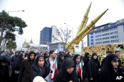 Iranians walk past a missile during a rally marking the 40th anniversary of the 1979 Islamic Revolution, in Tehran, Iran, Monday, Feb. 11, 2019.