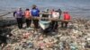 Nelayan Indonesia mendorong perahunya di antara sampah plastik yang memenuhi pantai Sukaraja di Bandar Lampung, 8 September 2019. (Photo by PERDIANSYAH / AFP)