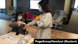 An employee has her temperature checked before entering PageGroup's office after reopening, as the coronavirus disease (COVID-19) continues, in Shanghai, China, April 29, 2020. (PageGroup/Handout via REUTERS)