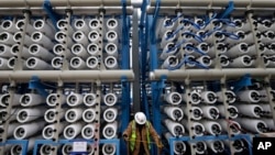 FILE - A worker climbs stairs among some of the 2,000 pressure vessels that will be used to convert seawater into fresh water through reverse osmosis in a desalination plant in Carlsbad, Calif., March 11, 2015. 