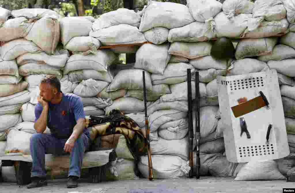 A supporter of the self-proclaimed Donetsk People's Republic sits behind a newly erected barricade on the airport road in the eastern Ukrainian city of Donetsk, May 28, 2014.