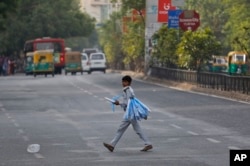 An Indian boy who sells toy planes at a traffic intersection reacts to camera as he crosses a road on the eve of World Day Against Child Labor in Ahmadabad, India on June 11, 2016.
