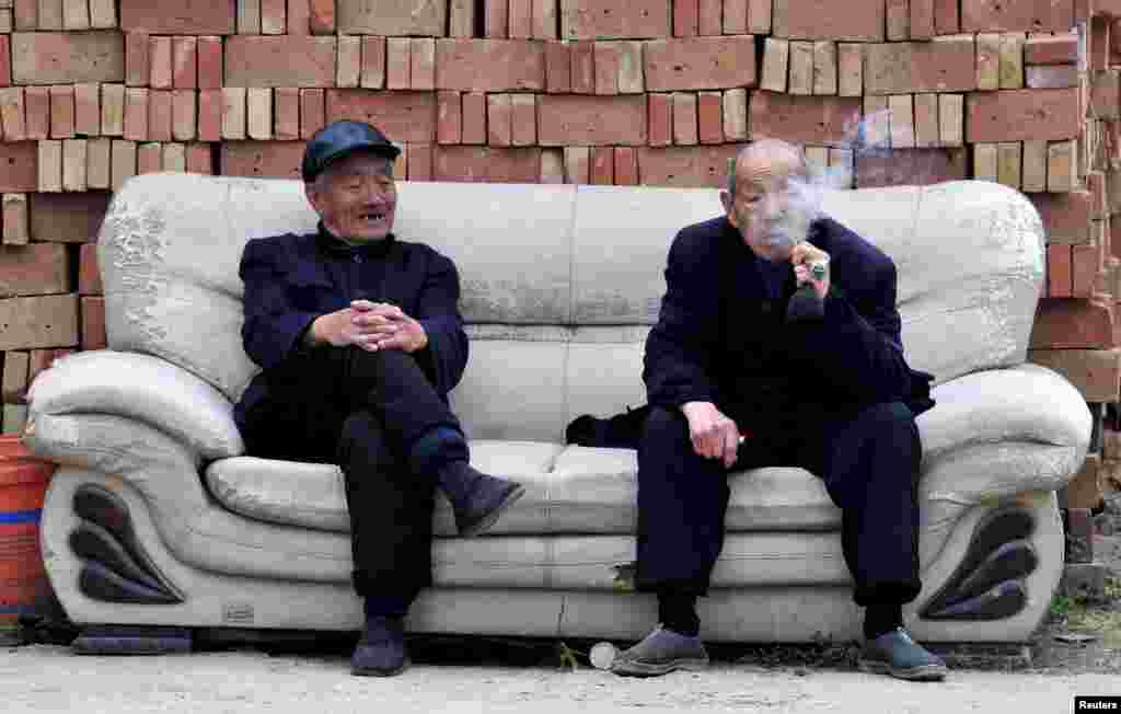 مرد مسنی در طرف راست عکس در حال گپ زدن با مرد مسن ديگری در مقابل انبوهی از آجر چپق می&zwnj;کشد. يونگجی، ايالت شان&zwnj;کسی، چين - ۲۱ فروردين ۱۳۹۴ (۱۰ آوريل ۲۰۱۵)