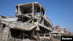 FILE - Buildings damaged during clashes between troops loyal to Libya's eastern government and the Shura Council of Libyan Revolutionaries are seen during a cleanup of the debris in Benghazi, Libya April 24, 2016.