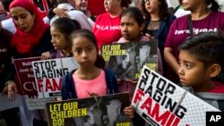 FILE - In this June 26, 2018, photo, children stand and hold protest signs during a rally in front of Federal Courthouse in Los Angeles. 