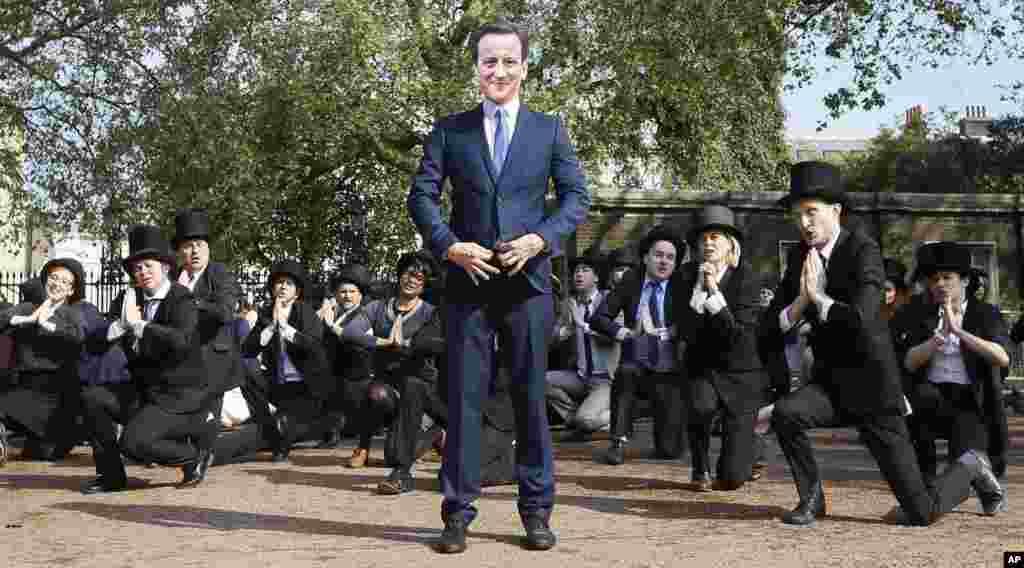 &#39;Artful Tax Dodgers&#39; flash mob including a protester wearing a mask of Britain&#39;s Prime Minister David Cameron, sing and dance at the entrance to Lancaster House, where the Anti-Corruption summit is taking place in London.