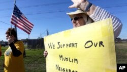 Jane Malin holds a sign as she waves to passing cars during a rally to show support for Muslim members of the community near the Clear Lake Islamic Center in Webster, Texas, Dec. 4, 2015. 