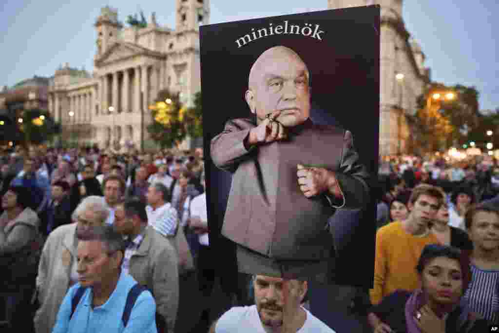 A man holds a banner depicting Hungarian Premier Viktor Orban, the reads "mini-prime minister" during a protest against Orban's policies regarding migrants in Budapest, Hungary, Sept. 30, 2016. 