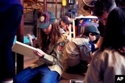미국 뉴햄프셔스주 매드버리에서 진행된 컵스카우트(Cub Scout) 모임에서 소녀가 공구 상자를 만들기 위해 파일럿 홀을 뚫고 있다.