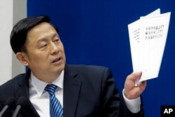 State Council Information Office spokesman, Guo Weimin holds up white policy paper on South China Sea during a press briefing at the State Council Information Office in Beijing, Wednesday, July 13, 2016.