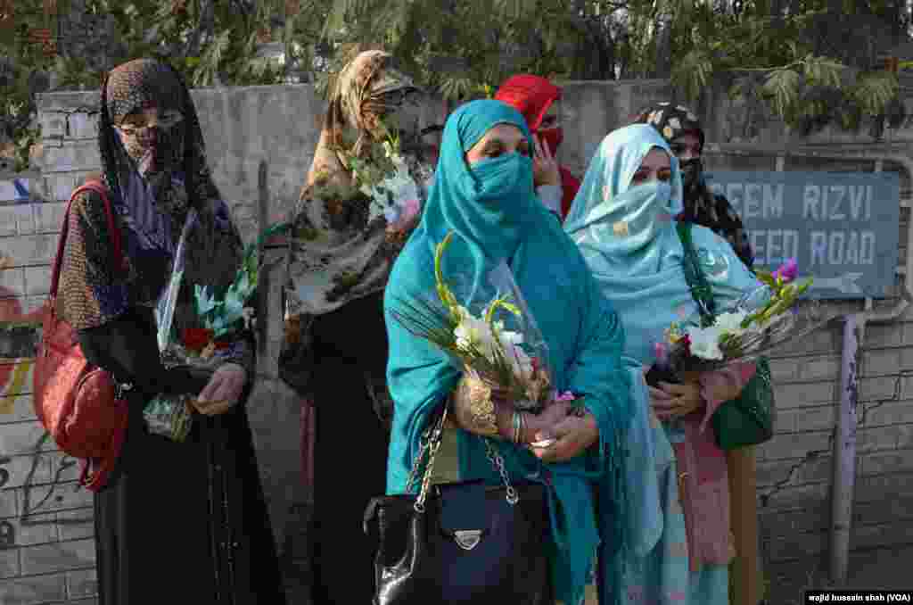خواتین حملے میں مرنے والوں کی یاد میں پھول لے کر کھڑی ہوئی ہیں۔