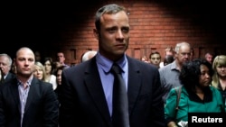 Oscar Pistorius awaits the start of court proceedings while his brother Carl (L) looks on, in the Pretoria Magistrates court February 19, 2013.