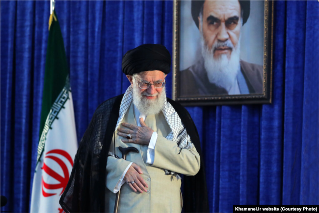 FILE - Iranian Supreme Leader Ayatollah Ali Khamenei gestures to a crowd at a June 4, 2019, ceremony in Tehran marking the 30th anniversary of the death of his predecessor, Ayatollah Ruhollah Khomeini, whose portrait appears behind him.
