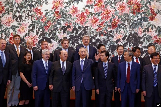 2018年6月初,美国代表团与中国代表团合影时美国商务部长罗斯与中国副总理刘鹤寒暄。从照片上看,前排中间5人是(左起)美国驻华大使布兰斯塔德,美国商务部长罗斯,中国副总理刘鹤,中国商务部长钟山和中国人民银行行长易纲。