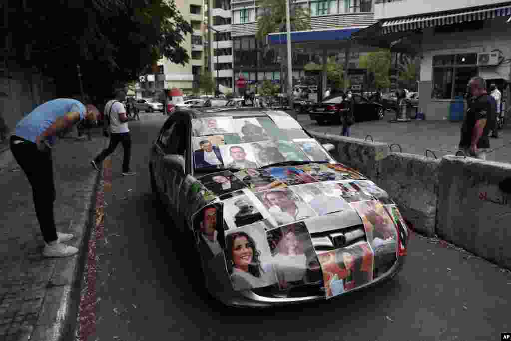 A Lebanese man whose relative died in last year&#39;s massive blast at Beirut&#39;s seaport, covers his car with portraits of those who died in the explosion, during a protest in front of the Justice Palace in Beirut, Lebanon, Friday, July 23, 2021. (AP Photo/Bil