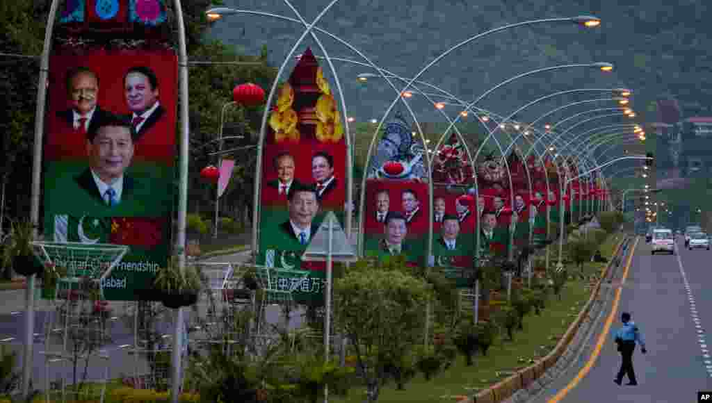 A Pakistani police officer walks past billboards showing pictures of Chinese President Xi Jinping, center, with Pakistan's President Mamnoon Hussain, left, and Prime Minister Nawaz Sharif welcoming Xi Jingping to Islamabad.