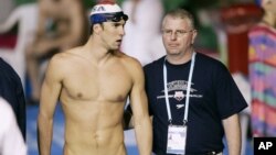 FILE - In this March 2007 file photo, U.S. swimming star Michael Phelps, left, walks with his coach Bob Bowman during a training session at the World Swimming Championships in Melbourne, Australia.