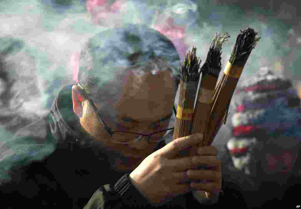 A Chinese man burns incense while offering prayers on the first day of the new year at the Yonghegong Lama Temple, Beijing, China, Jan. 1, 2014. 