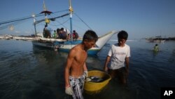 FILE - Filipino fishermen bring their fish to shore in the coastal town of Infanta, Pangasinan province, northwestern Philippines. 