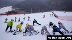 School children warm up before skiing at the Vanke Shijinglong Ski Resort in Yanqing outside of Beijing, China, on December 23, 2021. (AP Photo/Ng Han Guan)