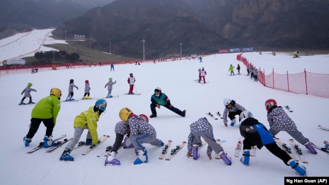 School children warm up before skiing at the Vanke Shijinglong Ski Resort in Yanqing outside of Beijing, China, on December 23, 2021. (AP Photo/Ng Han Guan)