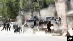 Security forces run from the site of a suicide attack after the second bombing in Kabul, Afghanistan, Monday, April 30, 2018. A coordinated double suicide bombing hit central Kabul on Monday morning, (AP Photo/Massoud Hossaini)