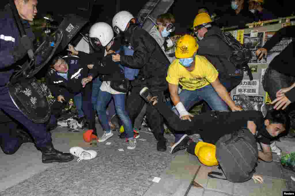 A protester falls on the ground as a group of them are chased by riot police outside the Legislative Council in Hong Kong, early morning of Nov. 19, 2014.