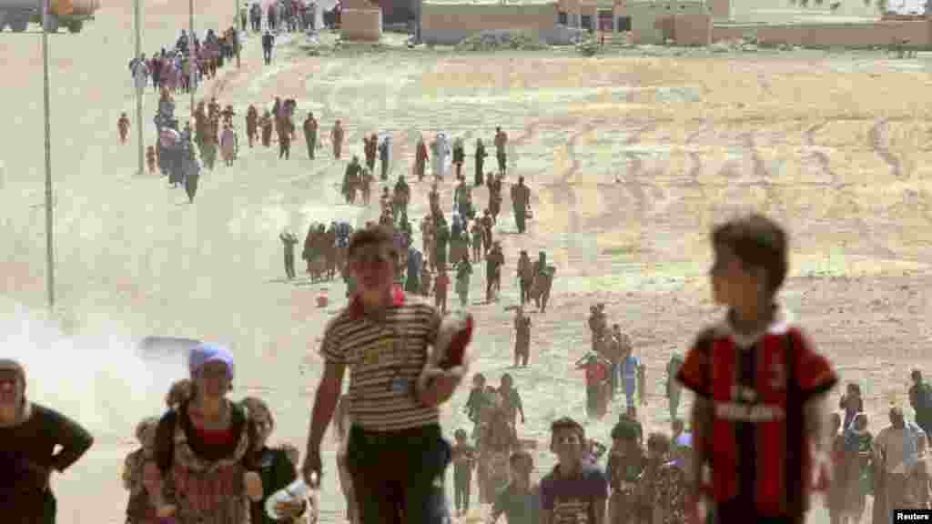Displaced people from the minority Yazidi sect, fleeing violence from forces loyal to the Islamic State in Sinjar town, walk towards the Syrian border, on the outskirts of Sinjar mountain, Aug. 10, 2014.
