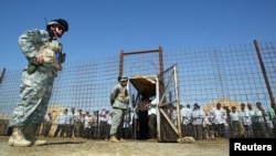 FILE - U.S soldiers stand guard as Iraqi prisoners wait to be released at Abu Ghraib prison, west of Baghdad, June 23, 2006. 
