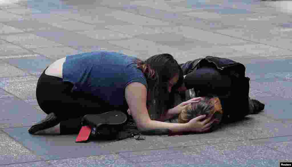 A woman attends to an injured man on the sidewalk in Times Square after a speeding vehicle struck pedestrians on the sidewalk in New York City.