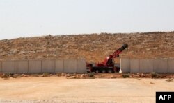 A picture taken in the Syrian village of Kafr Lusein, north of the Bab al-Hawa border crossing, Oct. 7, 2017, shows a crane parked next to a 3-meter-high fortification, built by the Turkish government along its border with Syria. The Britain-based Syrian Observatory for Human Rights monitor said Turkish army cranes had begun removing sections of the security wall Turkey has built on the border in preparation for an incursion.