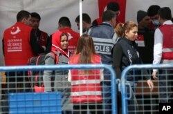 A Turkish police officer speaks with a migrant after a vessel transporting migrants from Greek island Chios docked in Dikili port, Turkey, April 4, 2016.