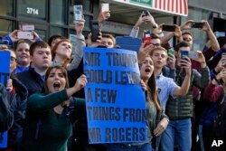 University of Pittsburgh sophomore Lynne Jaworski, from Homer City, Pa., holds a sign and yells as President Donald Trump's motorcade arrives at the University of Pittsburgh's Presbyterian Hospital, Oct. 30, 2018.