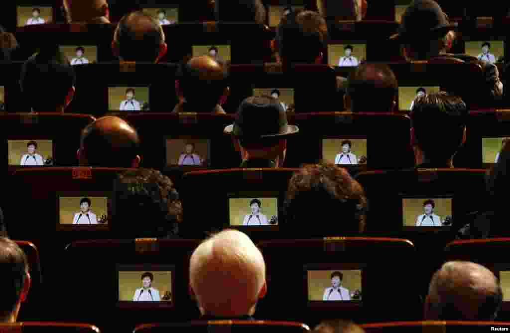 People watch South Korean President Park Geun-hye&#39;s speech on small screens fitted in their seats during a ceremony celebrating the 96th anniversary of the Independence Movement Day in Seoul.