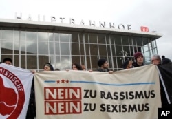 People protest in front of the main station in Cologne, Germany, on Wednesday, Jan. 6, 2016. The poster reads: "No to Racism, No to Sexism". More women have come forward alleging they were sexually assaulted and robbed during New Year’s Eve.
