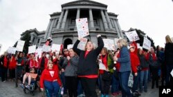 FILE - Stephanie Rolf, center, a teacher in the Douglas County, Colorado, school system, leads a cheer during a teacher rally in Denver, April 26, 2018.