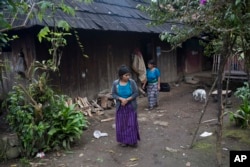 Catarina Alonzo Perez, mother of Felipe Gomez Alonzo, and her sister-in-law Maria, step outside their home in Yalambojoch, Guatemala, Dec. 29, 2018.