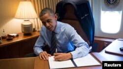 President Barack Obama signs two presidential memoranda associated with executive actions on immigration from his office on Air Force One upon his arrival in Las Vegas, Nevada, Nov. 21, 2014.