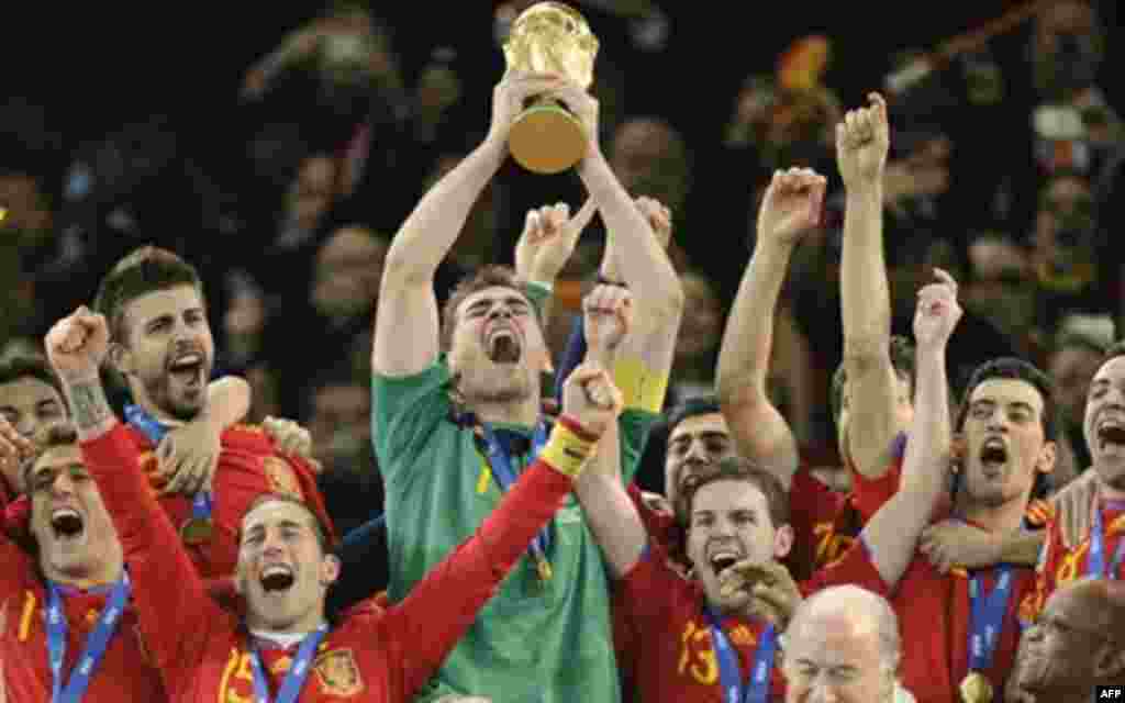 Spain goalkeeper Iker Casillas, center, holds up the World Cup trophy as he and other team members celebrate, as South African President Jacob Zuma, front right, and FIFA president Sepp Blatter, second from right in front, look on during the World Cup fin