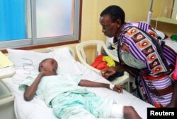 A woman talks to a child injured when Italian volunteer was seized in Chakama trading centre of Magarini, as he receives treatment at the Malindi district hospital in Malindi, Kenya, Nov. 21, 2018.