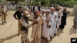 A Pakistani paramilitary soldier checks voters before they enter a polling station to cast their ballots, in Karachi, Pakistan, May 11, 2013.