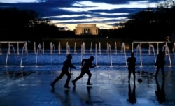 FILE - Tourists visit the National World War II Memorial on the east end of the Reflecting Pool and Lincoln Memorial as a storm clears the nation's capital in Washington.