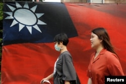 人们从台北街头的台湾旗帜旁走过。（2020年8月10日）