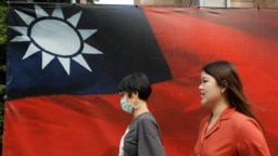 人们从台北街头的台湾旗帜旁走过。（2020年8月10日）