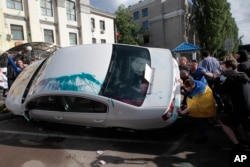 Ukrainian protesters turn over cars near the Russian Embassy during a rally in Kyiv, Ukraine, June 14, 2014.