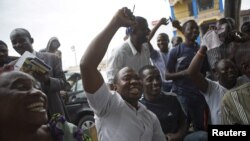 Supporters of presidential candidate Muhammadu Buhari cheer as they watch news coverage of election results favourable to them on a street in Lagos, March 31, 2015. The opposition All Progressives Congress (APC) declared victory for its candidate, former 